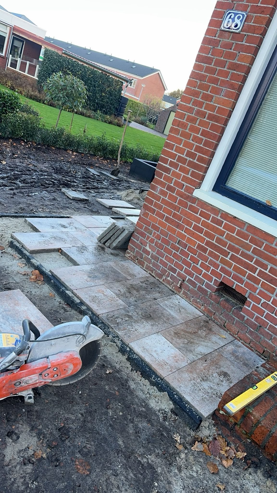 Aanleg van grote terrastegels langs een woning