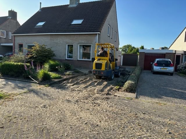 Minigraver tijdens grondwerk in een voortuin