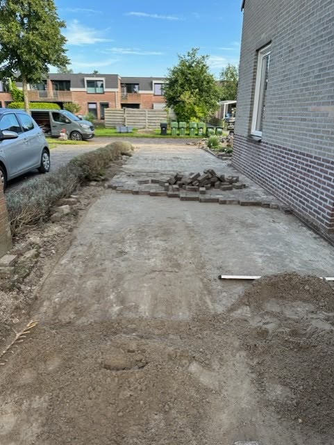 Grondwerk tussen twee woningen voor nieuwe bestrating